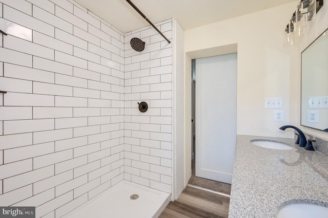 bathroom with wood-type flooring, vanity, and a tile shower