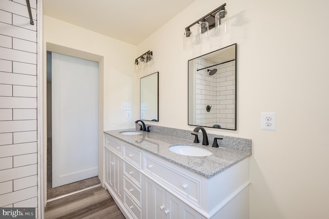 bathroom with hardwood / wood-style floors, vanity, and tiled shower