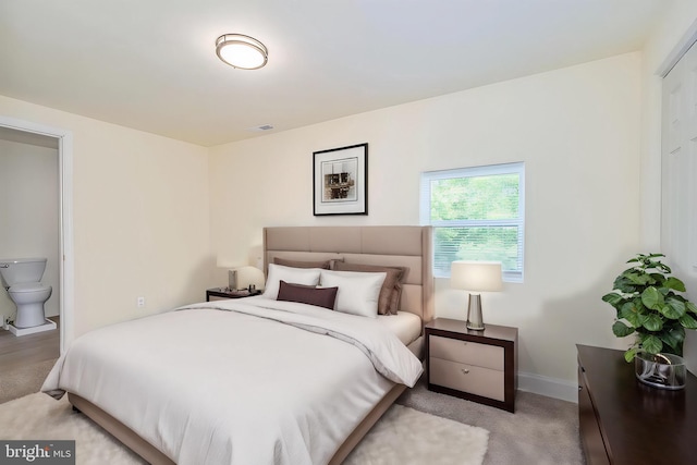 bedroom with light carpet and ensuite bath