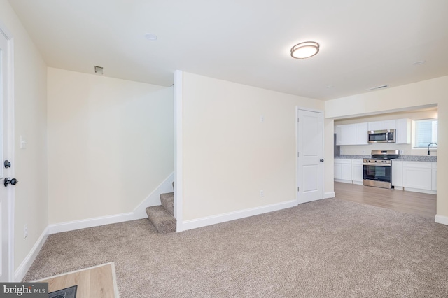 unfurnished living room featuring light carpet and sink