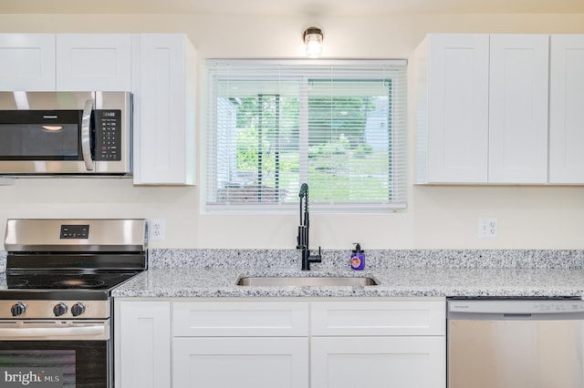 kitchen with appliances with stainless steel finishes, white cabinetry, and sink