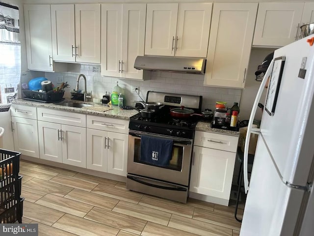 kitchen featuring white cabinets, white refrigerator, sink, and gas range