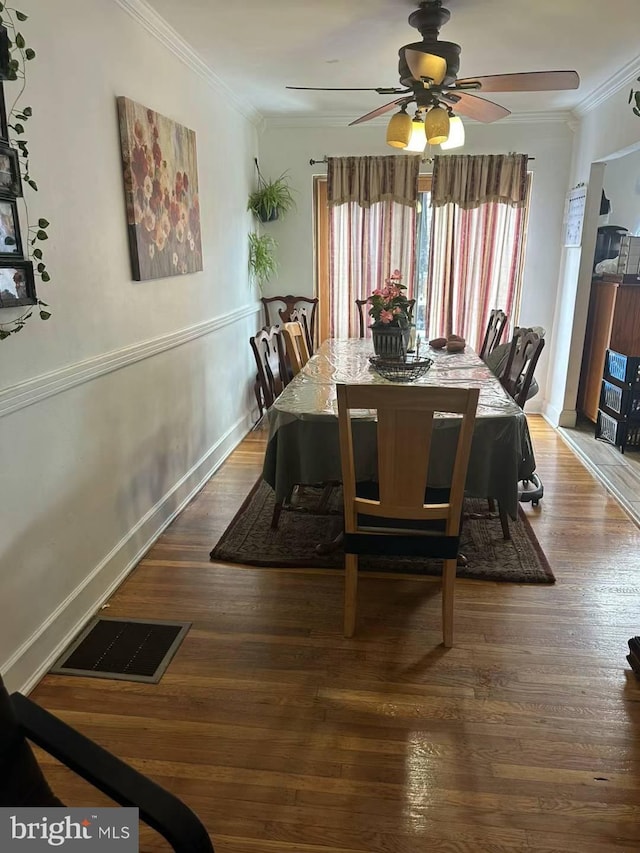 dining space with ceiling fan, dark wood-type flooring, and ornamental molding