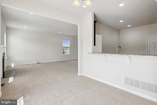 kitchen with baseboards, visible vents, light stone countertops, carpet floors, and recessed lighting