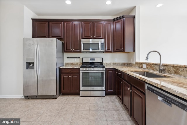 kitchen featuring stainless steel appliances, recessed lighting, a sink, dark brown cabinetry, and light stone countertops