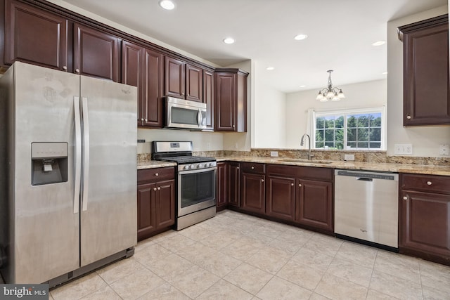 kitchen featuring dark brown cabinetry, appliances with stainless steel finishes, light stone counters, and a sink