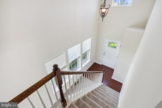 staircase with a towering ceiling, baseboards, and wood finished floors