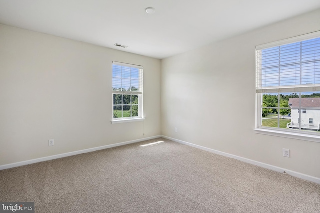 spare room with carpet floors, visible vents, and baseboards