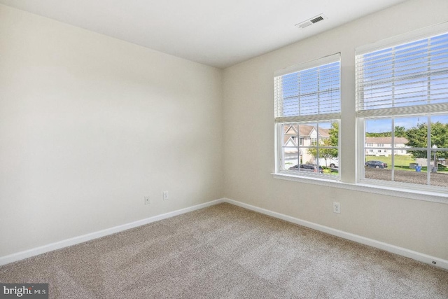 carpeted empty room featuring visible vents and baseboards