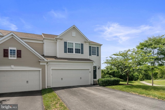 view of property featuring an attached garage, a front lawn, and aphalt driveway