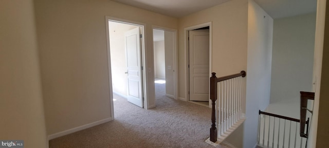 hall with an upstairs landing, carpet, and baseboards