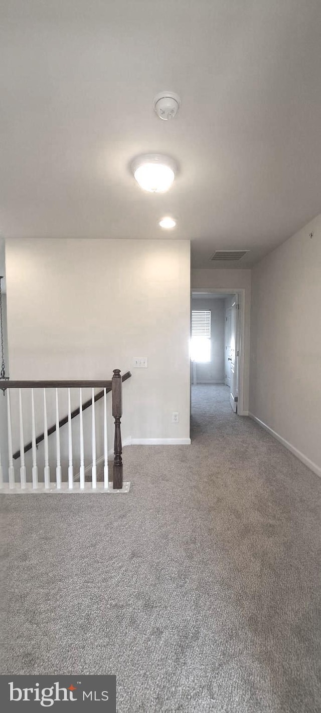 carpeted empty room with visible vents and baseboards