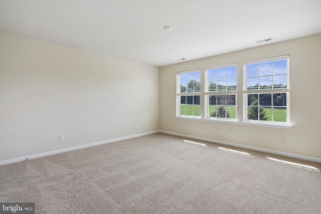 spare room featuring carpet floors, visible vents, and baseboards