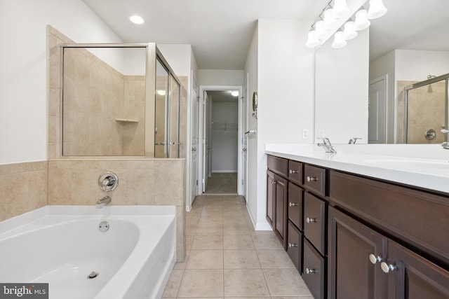 bathroom with double vanity, a stall shower, a garden tub, tile patterned flooring, and a sink