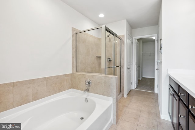 bathroom with a walk in closet, a garden tub, a stall shower, vanity, and tile patterned floors