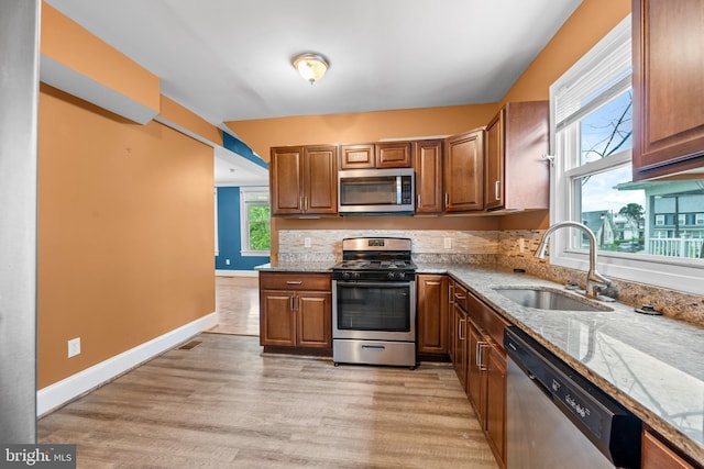 kitchen with light stone counters, sink, light hardwood / wood-style flooring, and appliances with stainless steel finishes