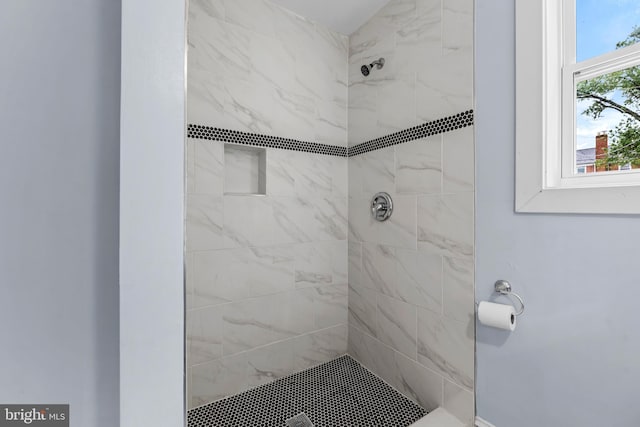 bathroom with tiled shower and a healthy amount of sunlight