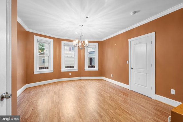 spare room with light hardwood / wood-style floors, an inviting chandelier, and crown molding