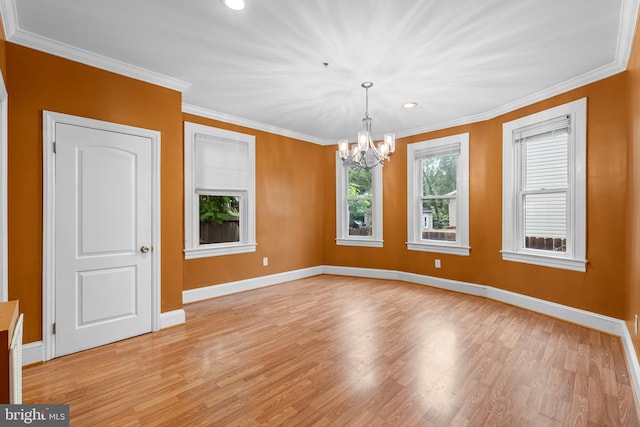 spare room with an inviting chandelier, ornamental molding, and light hardwood / wood-style flooring