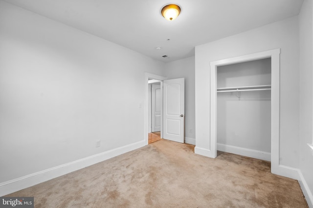 unfurnished bedroom featuring light carpet and a closet