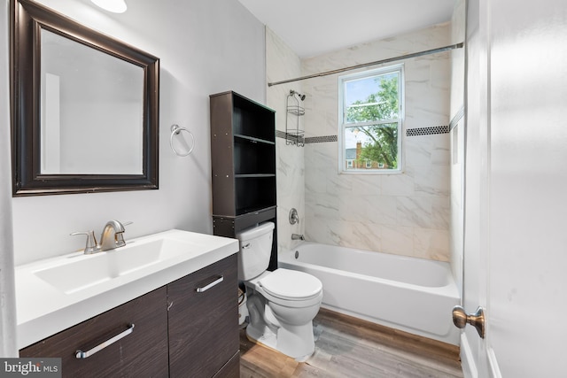 full bathroom featuring vanity, wood-type flooring, tiled shower / bath combo, and toilet