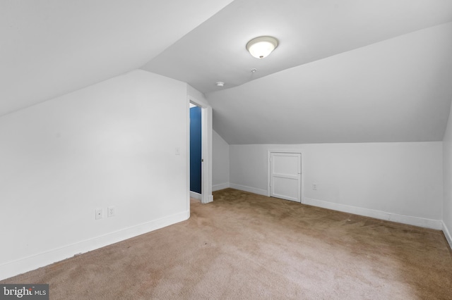 additional living space featuring light colored carpet and vaulted ceiling