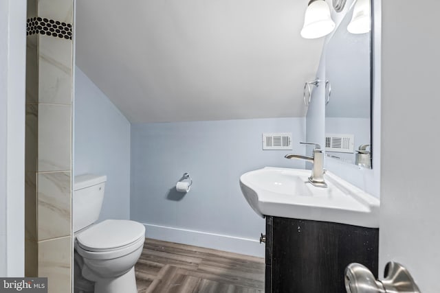 bathroom with hardwood / wood-style floors, vanity, vaulted ceiling, and toilet