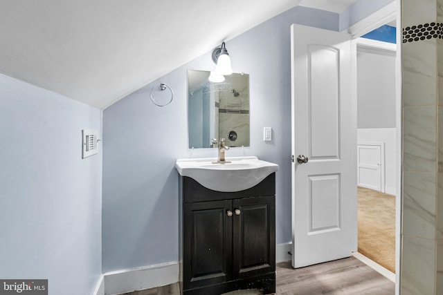 bathroom featuring vanity, hardwood / wood-style flooring, and vaulted ceiling