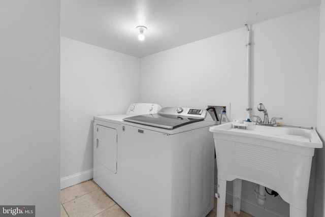 clothes washing area with separate washer and dryer, sink, and light tile patterned floors