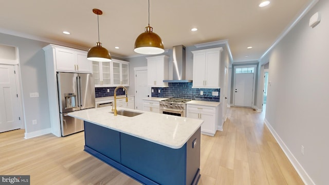 kitchen featuring wall chimney range hood, sink, hanging light fixtures, premium appliances, and white cabinetry