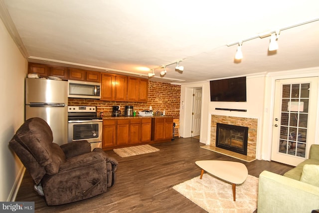 living room with a fireplace, rail lighting, dark hardwood / wood-style floors, and ornamental molding