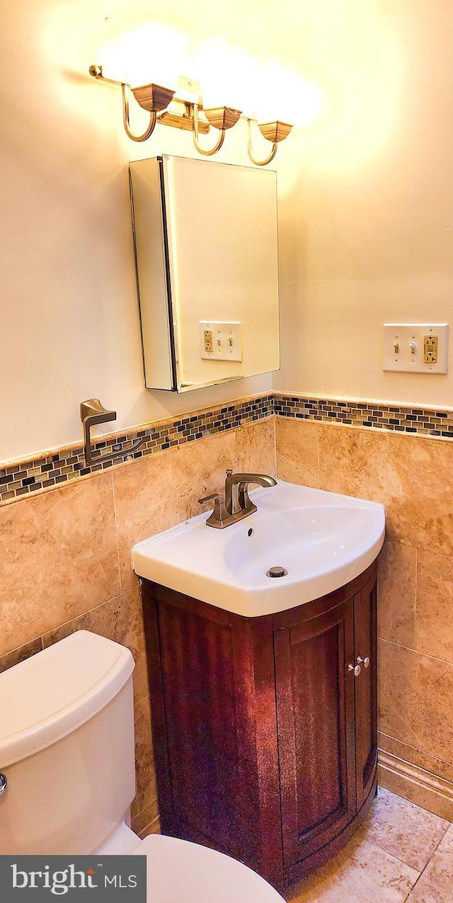 bathroom featuring tile patterned floors, vanity, toilet, and tile walls