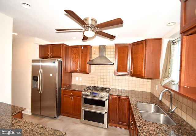 kitchen with sink, wall chimney exhaust hood, dark stone countertops, tasteful backsplash, and stainless steel appliances