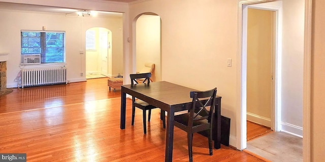 dining space featuring radiator heating unit, light wood-type flooring, and crown molding