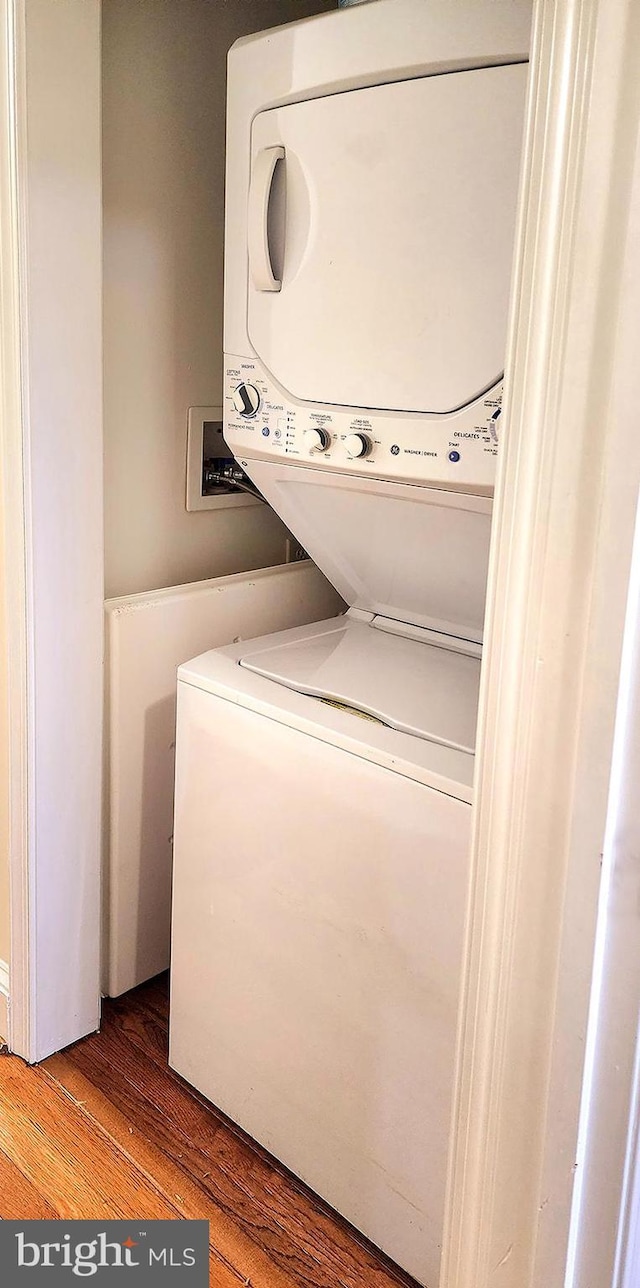 laundry area featuring stacked washing maching and dryer and hardwood / wood-style flooring