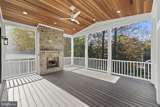 unfurnished sunroom featuring an outdoor stone fireplace, ceiling fan, wood ceiling, and lofted ceiling