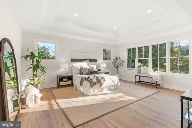 bedroom featuring a raised ceiling and light hardwood / wood-style flooring