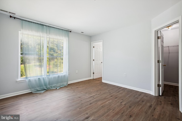 unfurnished bedroom featuring a closet, hardwood / wood-style flooring, and a walk in closet