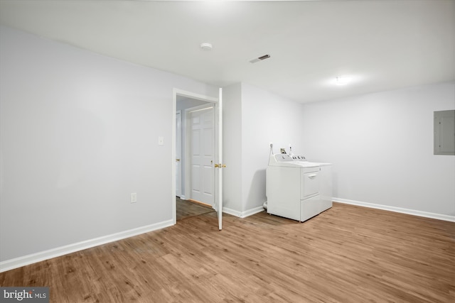 clothes washing area with washing machine and clothes dryer, light hardwood / wood-style floors, and electric panel