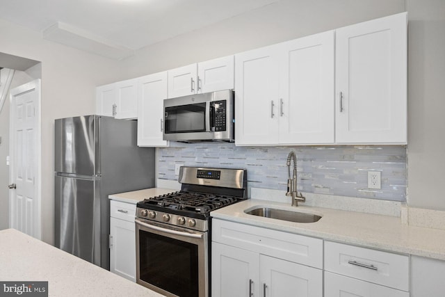 kitchen featuring decorative backsplash, sink, white cabinetry, and stainless steel appliances