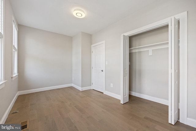 unfurnished bedroom featuring a closet and hardwood / wood-style flooring