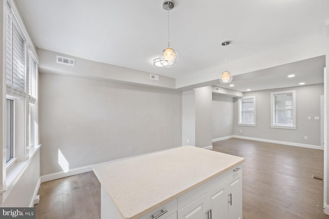 kitchen featuring white cabinetry, dark wood-type flooring, a kitchen island, and hanging light fixtures