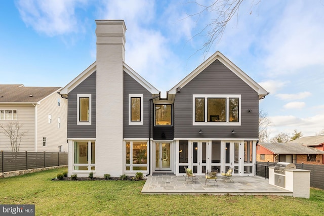 rear view of property with an outdoor kitchen, a patio area, and a lawn