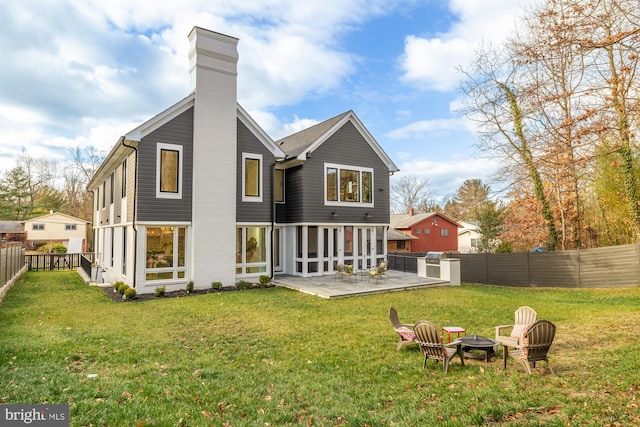 rear view of property featuring an outdoor fire pit, a patio, and a yard