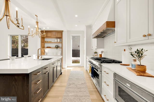 kitchen with stainless steel appliances, sink, decorative light fixtures, white cabinets, and custom exhaust hood