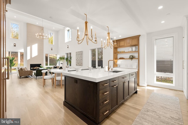 kitchen featuring sink, a fireplace, a healthy amount of sunlight, a center island with sink, and pendant lighting