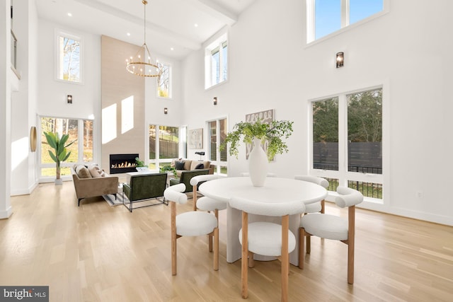 dining room with a high ceiling, light hardwood / wood-style flooring, a chandelier, and a fireplace