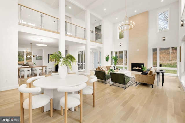 dining area with a high ceiling, a fireplace, light hardwood / wood-style floors, and a notable chandelier