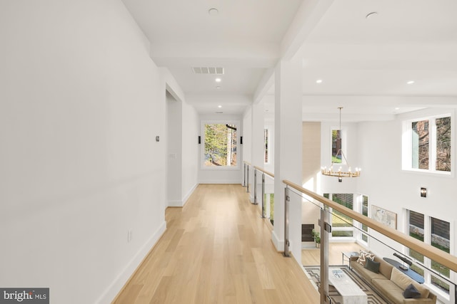 hallway featuring beam ceiling, a notable chandelier, and light hardwood / wood-style floors