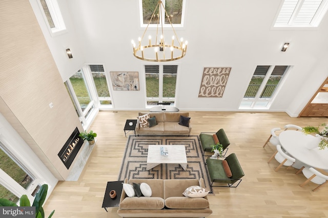 living room with a high ceiling, light hardwood / wood-style floors, and a notable chandelier